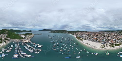 360 aerial photo taken with drone of boat marina full of small boats next to commercial beach