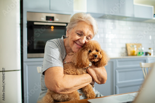 Elderly woman with her dog working on laptop at home