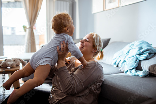 Mother playing with her toddler in the living room photo
