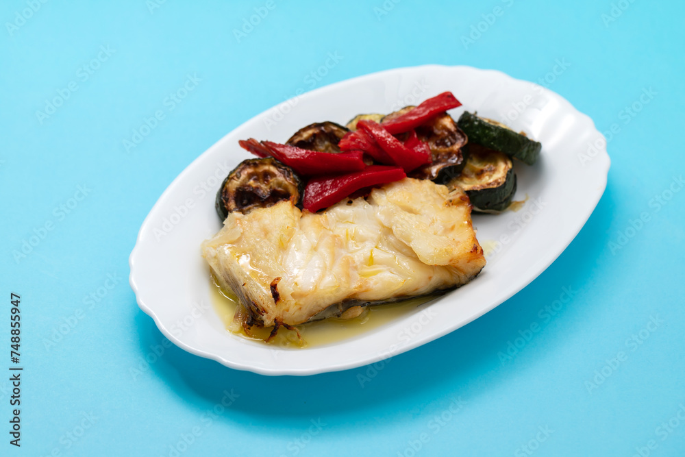 Fish dish - fried cod fish with grilled vegetables in plate Fish dish - fried cod fish with grilled vegetables in plate