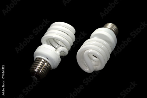 Two energy saving spiral bulbs isolated on black background studio shot
