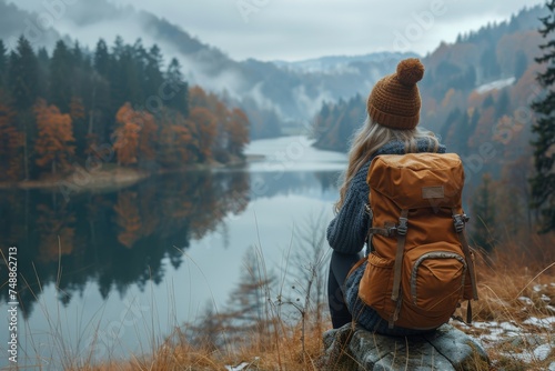 A lone traveler sits contemplating a serene misty lake surrounded by autumn colors, evoking wanderlust and reflection
