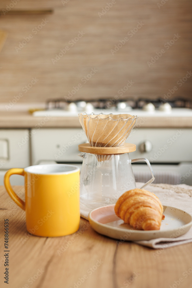 black coffee in morning kitchen. brews in purover. yellow cup with black coffee drip. daily routine of happy start to day. Food and drinks, croissant on table. Americano cappuccino for cheerfulness black coffee in morning kitchen. brews in purover. yellow cup with black coffee drip. daily routine of happy start to day. Food and drinks, croissant on table. Americano cappuccino for cheerfulness