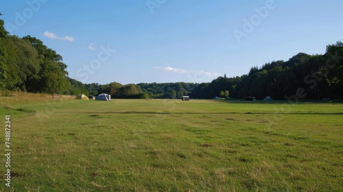 a large field at a campsite, an open space in the middle, camera eye level and looking straight ahead. 