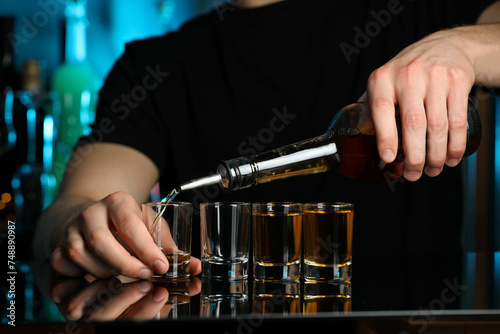 Bartender pouring alcohol drink into shot glass at mirror counter in bar  closeup
