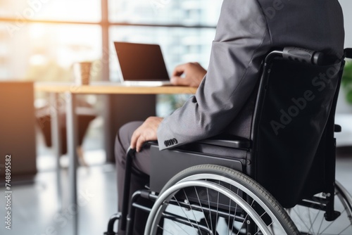 physically disabled person sits in a wheelchair and works in the office. Disabled people with disabilities can work like normal people. © venusvi