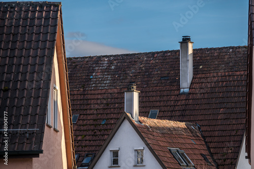 Detail Hausdächer mit Schornsteinen vor blauem Himmel mit Wolken