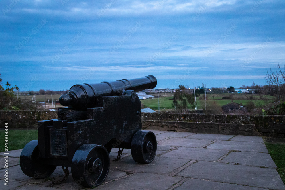 Canon in the Rye castle grounds looking out towards the sea and land in-between, on a cloudy day just after sunset 