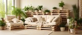 The living room is adorned with various furniture pieces such as a sofa, armchairs, and a DIY pallet bed, all in earthy beige tones. Numerous potted plants are scattered throughout the room,