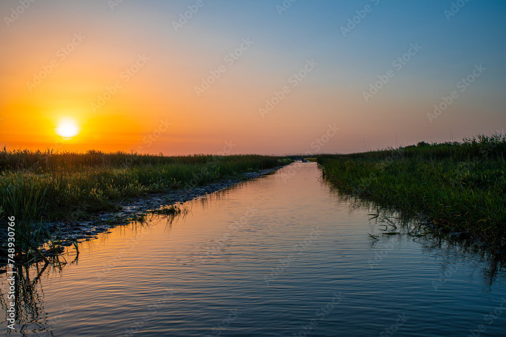 Obraz premium Golden Pathway: Sunset Waterway Among Reeds in Bojaq National Park, Iran
