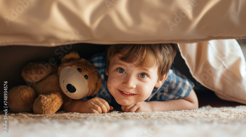 Garotinho brincando com ursinho de pelúcia na cama em casa. photo
