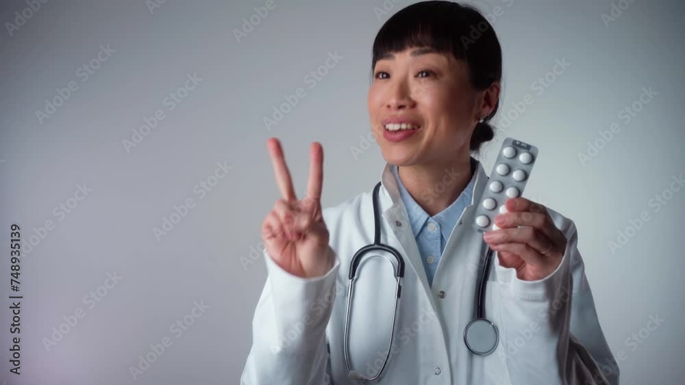 Happy Asian female doctor hand holding pack of different tablet blisters at workplace. Panacea, life save service, prescribe medicament, legal drug store, disease healing, blood pressure concept Happy Asian female doctor hand holding pack of different tablet blisters at workplace. Panacea, life save service, prescribe medicament, legal drug store, disease healing, blood pressure concept