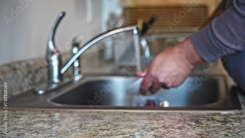 Manually cleaning dishes in kitchen sink during daytime