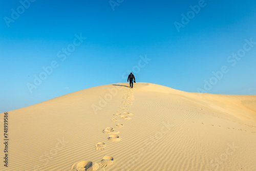 A male Photographer step by step walking on Desert Landscape in Abqaiq Dammam Saudi Arabia. photo