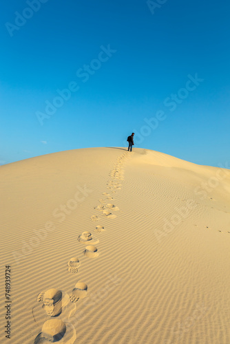 A male Photographer step by step walking on Desert Landscape in Abqaiq Dammam Saudi Arabia.