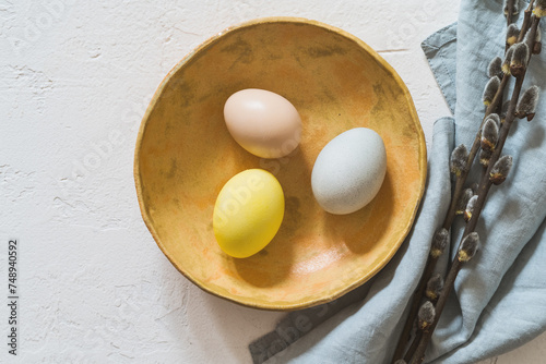Overhead shot of colourful Easter eggs and twigs on white rustic background