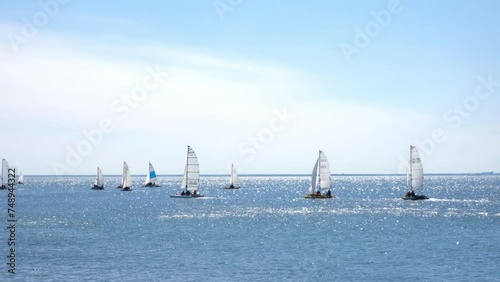 Sailing. Catamarans with white sails in open sea. Sports competitions on high seas. Regatta. Moving in wind on a sailing boat. Boat trip on yacht. Recreation, leisure, cruise. photo