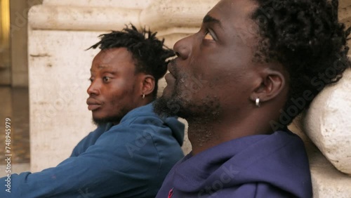 despair, misery - two  jobless migrants sitting on the street looking distressed photo