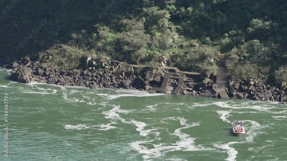 tour boat cruising on the river at the foot of the iguazu falls at the border between Brazil and Argentina. tour boat cruising on the river at the foot of the iguazu falls at the border between Brazil and Argentina.