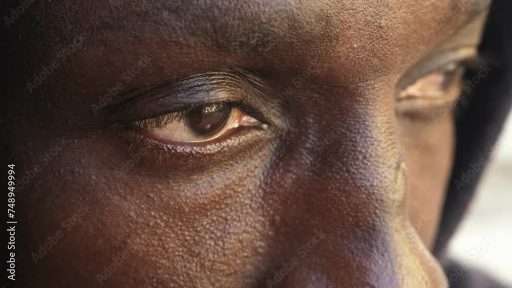 close up on african hooded man looks away with sad look close up on african hooded man looks away with sad look