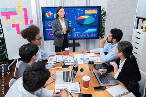 Young asian businesswoman presenting data analysis dashboard on TV screen in modern meeting. Business presentation with group of business people in conference room. Concord