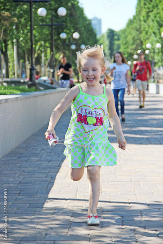 Happy little girl running in city park. Positive childish emotions © alexmak