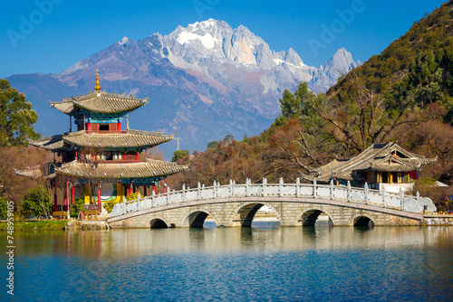 Bridge and pagoda pavilion at the Black Dragon Pool with Yulong Snow Mountain in the background. Lijiang, Yunnan, China photo