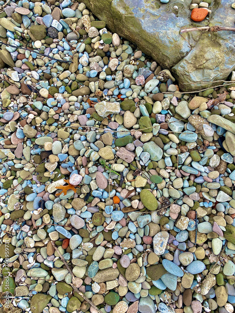 colorful rocks, pebbles and artifacts on a beach near a large boulder