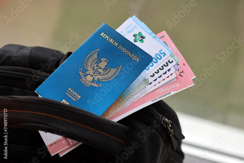 Blue Republic Indonesia passport with money and airline tickets on touristic backpack close up. Tourism and travel concept photo