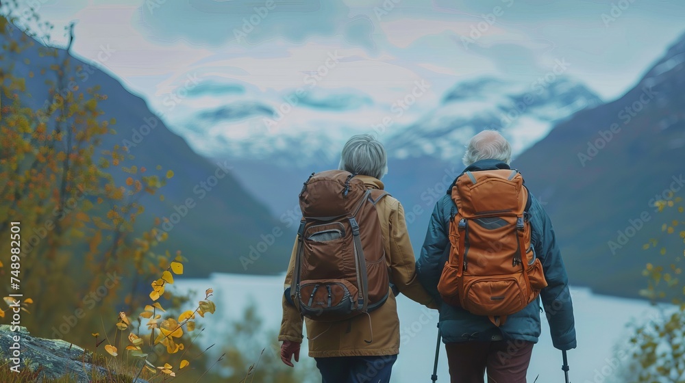 Back view of elderly couple with backpacks hiking in the mountains