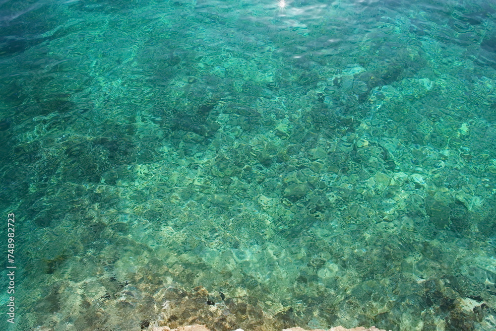 The water is clear and calm, with a rocky shoreline