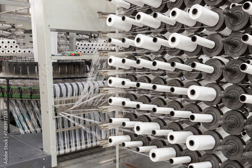 Factory equipment in perspective. Rows with coils of polypropylene threads for weaving cloth. Automatic machine. Nobody.