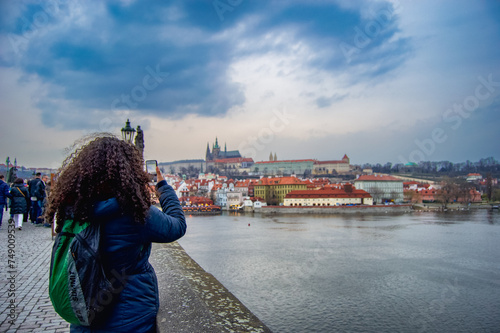 Woman taking a picture of the Prague Castle with her cellphone from Charles Bridge photo