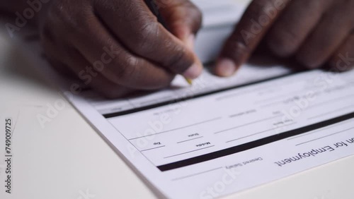 working abroad - black man fills out the application form for employment photo