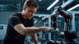 Selective focus at male engineer in casual work attire fine-tunes the components of a sophisticated robotic arm in a high-tech manufacturing environment.