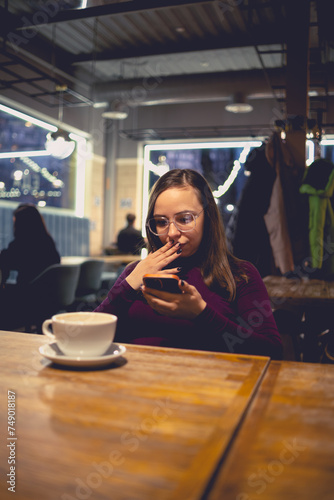 Woman Contemplating While Holding Smartphone in Coffee Shop