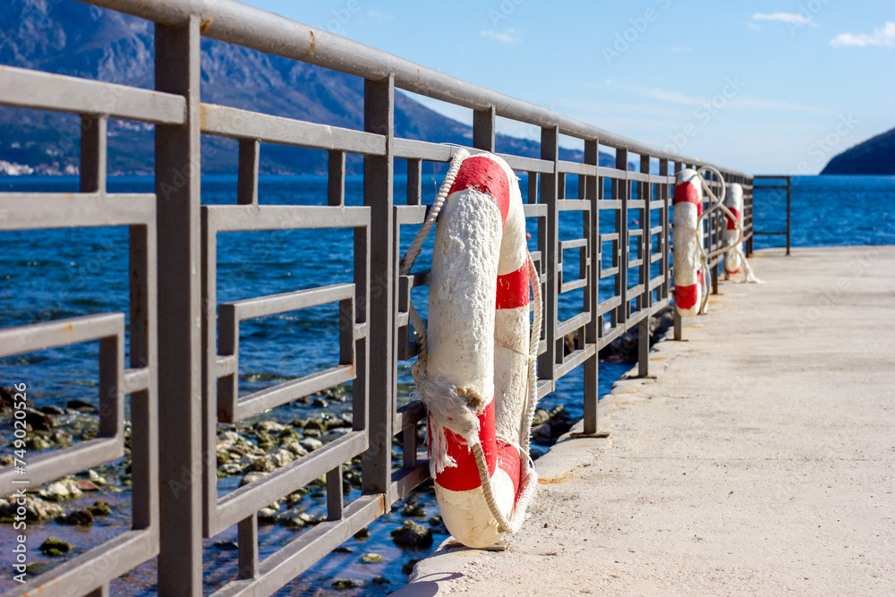 Obraz premium old lifebuoy, white-red, on the pier 