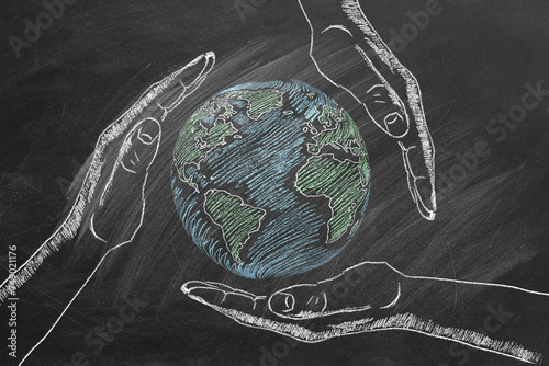 Rotating globe with male palms hand drawn in chalk on a school blackboard. Save our planet.