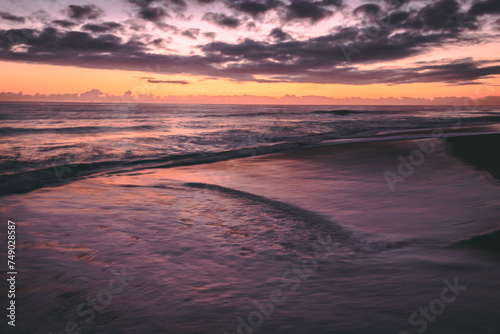 Sunrise on a Florida beach, sea foam on shore, clouds above the horizon