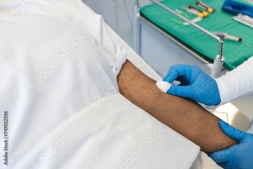 A healthcare professional is preparing a patient's arm for a procedure