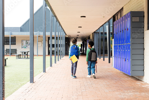 Biracial boy and African American boy walk down a school corridor