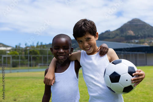 Biracial boy and African American boy smile, holding a soccer ball in school