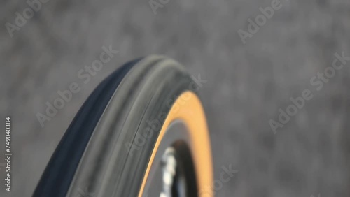 bike tire rolling on asphalt close up footage (bicycle wheel turning, riding on paved road path in a park) cyclist riding rubber tire with skinwall side (brown side wall) rim sidewall 650b cycling photo