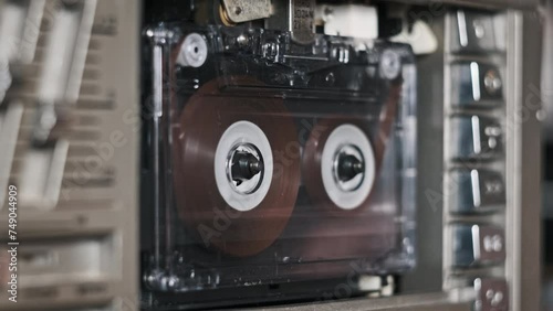 Audio tape recorder playback. Insert and eject vintage transparent audio cassette close-up. Record player playing an old tape. Retro tape reels rotate in a deck. Rec conversations, calls, archive, 80s photo
