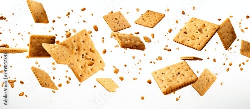 Numerous crunchy rectangular crackers are falling through the air onto a white surface in a burst of motion.