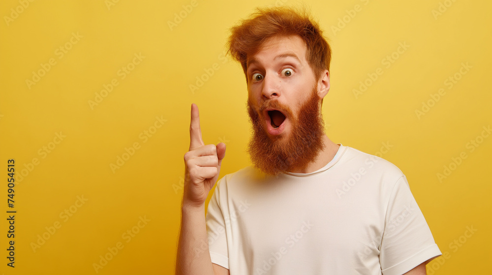 Homem ruivo barbudo com um dedo levantado e expressão de impressionado isolado no fundo amarelo
  - obrazy, fototapety, plakaty 
