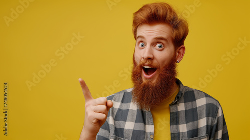 Homem ruivo barbudo com um dedo levantado e expressão de impressionado isolado no fundo amarelo
 
