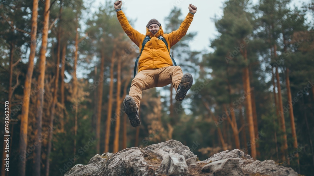 Happy man with arms up jumping on the top of the mountain - Successful hiker celebrating success on the cliff - Life style concept with young male climbing in the forest pathway.