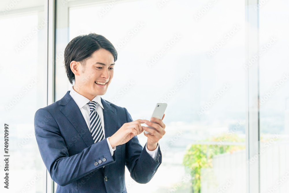 オフィスでスマホを使うアジア人男性ビジネスマン
オフィスでスマホを使うアジア人男性ビジネスマン