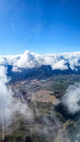 An aerial shot of southern California with vast buildings of homes and office buildings, majestic mountain ranges and blue sky with clouds in California USA